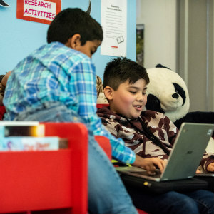 Two boys working at a laptop in the library