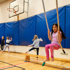 Girl swinging on ropes in the gym