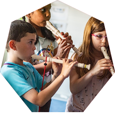 Three small children playing the recorder