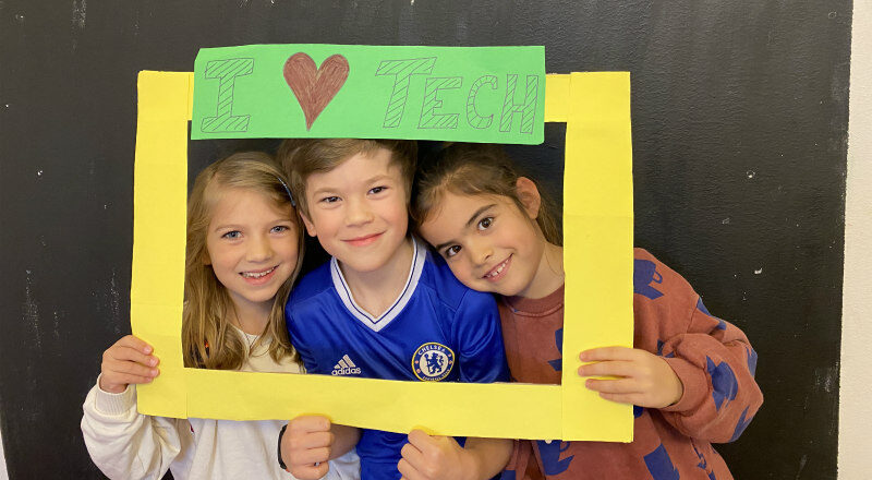Three children posing by a selfie frame saying I Love Tech