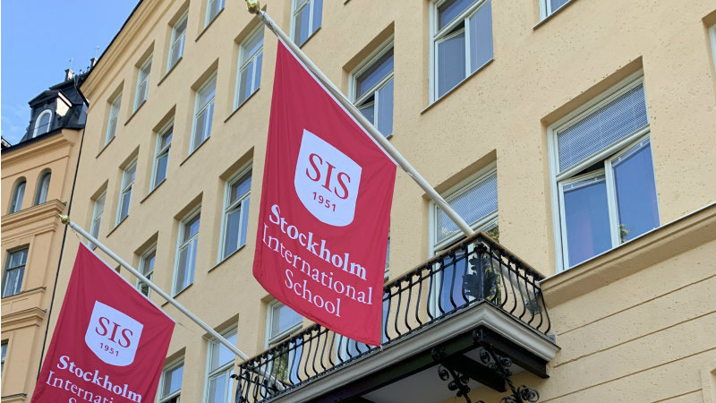 SIS branded flags on the main school building