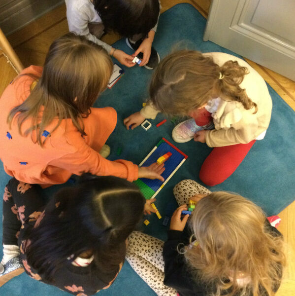Children gathered around an activity on the carpet